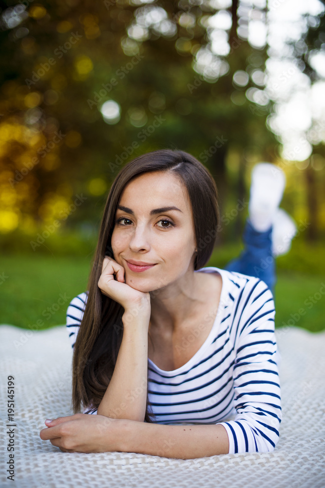 Close up portrait of pretty modern young woman in casual clothes resting in a city park lying on a plaid. Relax after work outdoors Close up portrait of pretty modern young woman in casual clothes resting in a city park lying on a plaid. Relax after work outdoors