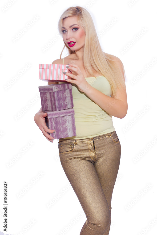 Studio photo of a beautiful young blond woman with long hair dressed in a summer light yellow jersey and golden jeans. The girl is holding boxes with gifts. A model poses against a white background. Studio photo of a beautiful young blond woman with long hair dressed in a summer light yellow jersey and golden jeans. The girl is holding boxes with gifts. A model poses against a white background.