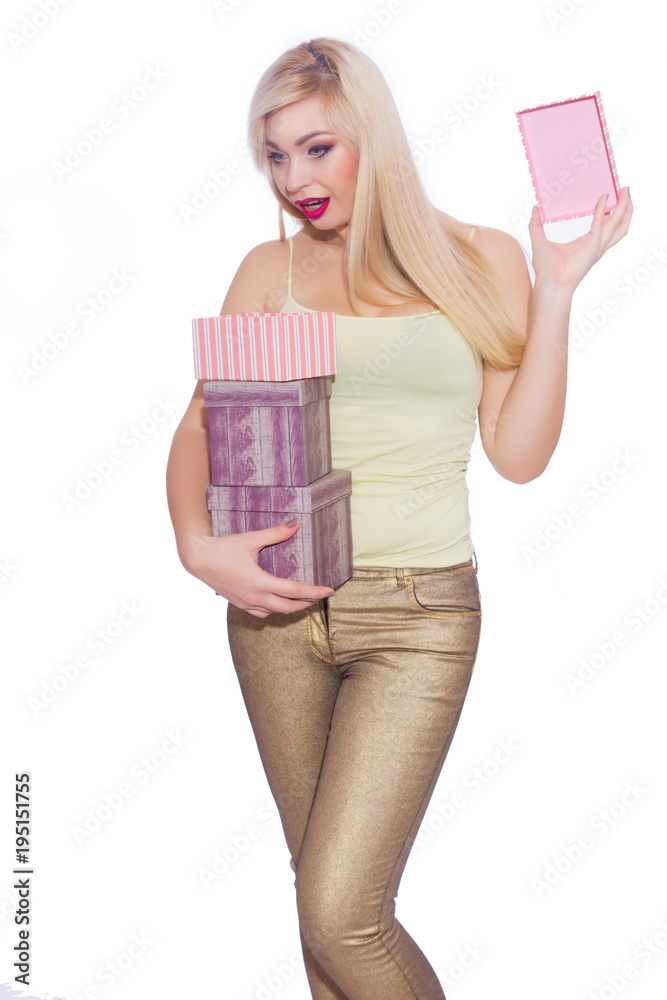 Studio photo of a beautiful young blond woman with long hair dressed in a summer light yellow jersey and golden jeans. The girl is holding boxes with gifts. A model poses against a white background. Studio photo of a beautiful young blond woman with long hair dressed in a summer light yellow jersey and golden jeans. The girl is holding boxes with gifts. A model poses against a white background.