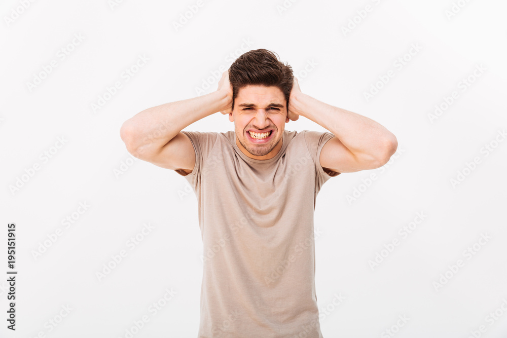 Photo of distressed emotional man 30s grabbing his head or covering ears in annoyance, isolated over white background Photo of distressed emotional man 30s grabbing his head or covering ears in annoyance, isolated over white background