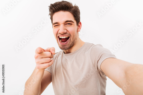 Fotografie Joyful man with brown hair gesturing index finger on camera meaning hey you whil