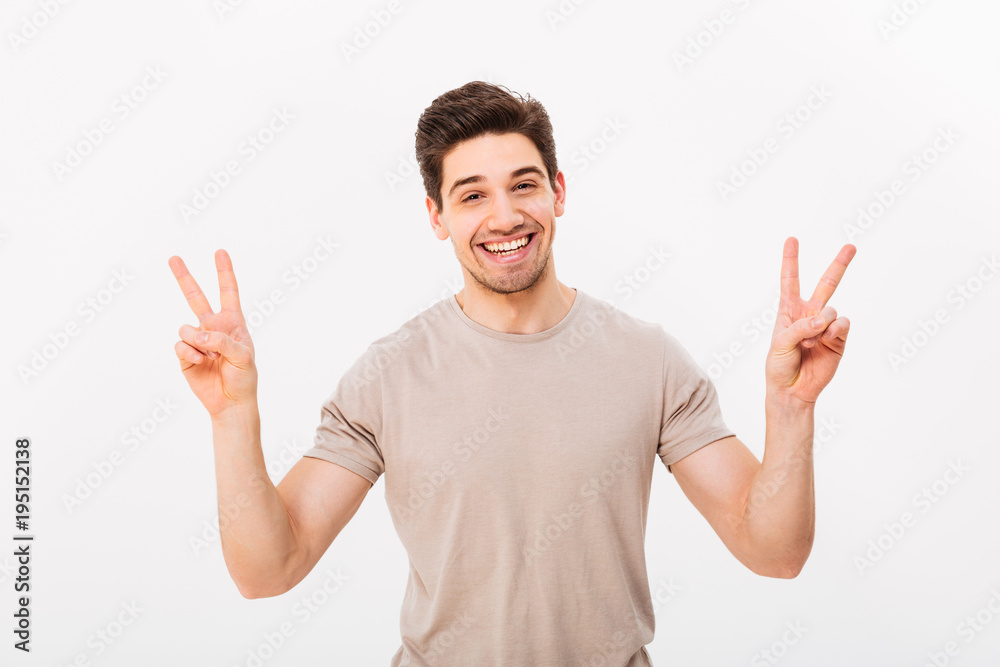 Studio photo of friendly guy model gesturing peace symbol with two hands and expressing gladness, isolated over white background Studio photo of friendly guy model gesturing peace symbol with two hands and expressing gladness, isolated over white background