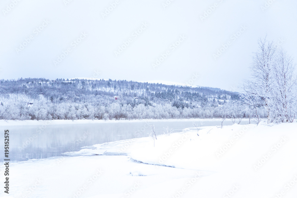 Beautiful frozen river with a trees on a bank. White winter landscape of central Norway. Light scenery. Beautiful frozen river with a trees on a bank. White winter landscape of central Norway. Light scenery.
