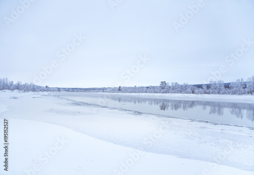 Beautiful frozen river with a trees on a bank. White winter landscape of central Norway. Light scenery. © dachux21