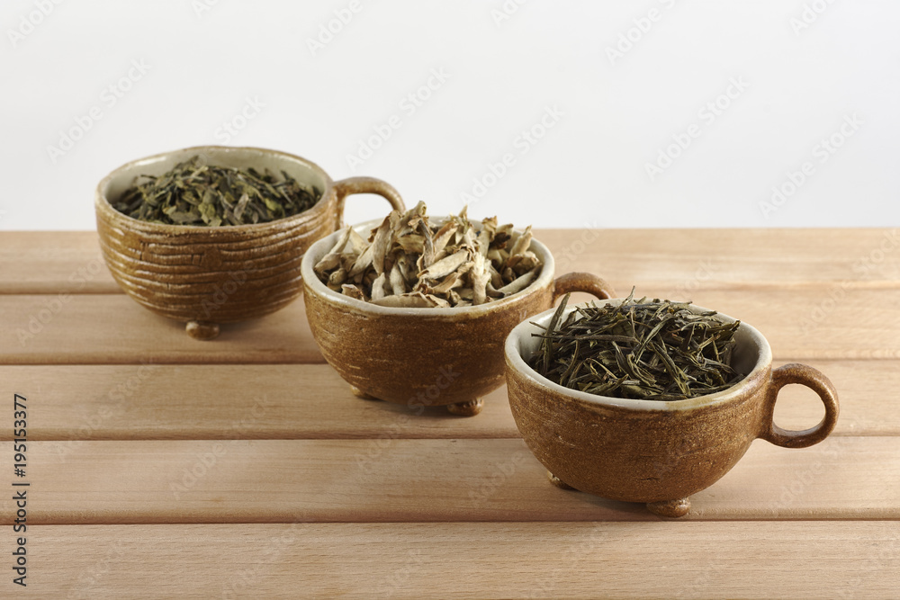 Three cups with green tea leaves on a white background Three cups with green tea leaves on a white background