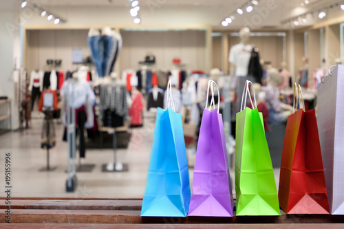 Paper shopping bags with shopping and gift, on the floor against with blurred clothes shop for display or montage your products