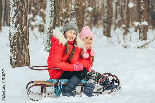 little children are sitting on a sled in the winter forest