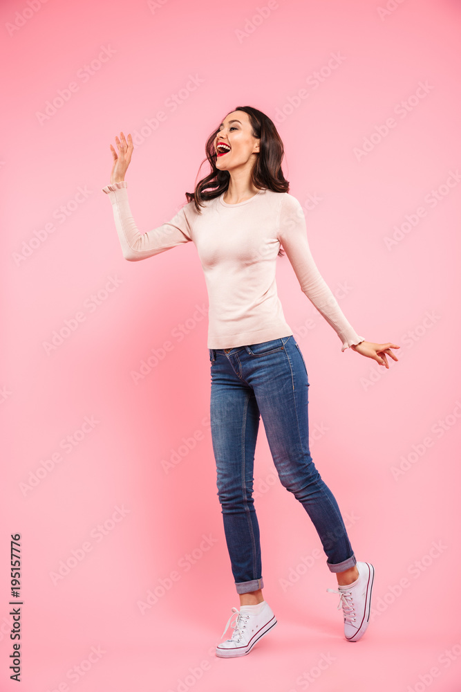 Full length photo of attractive woman 20s with long brown hair wearing jeans and sneakers rejoicing and touching copyspace, isolated over pink background Full length photo of attractive woman 20s with long brown hair wearing jeans and sneakers rejoicing and touching copyspace, isolated over pink background