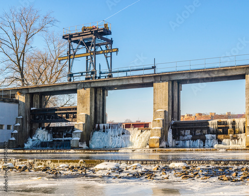 The dam on the river in the city in the winter. Icing of dam structures during the descent of water in winter