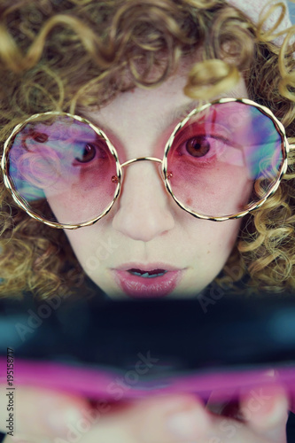 Mujer joven con gafas de sol rosas usando su teléfono móvil  photo