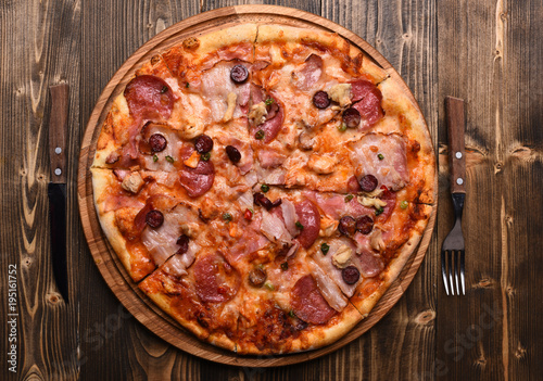 Italian dish with fork, knife. Pizza with bacon and cheese