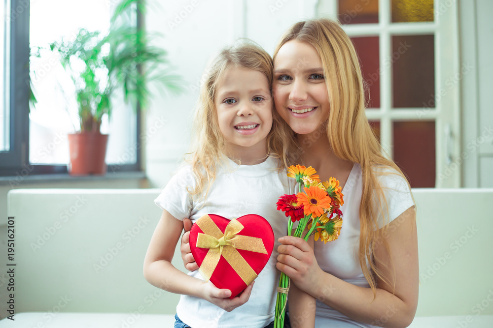 Beautiful cheerful mother and a little smiling daughter embrace with gifts in their hands and look at the camera. Birthday. March 8. Women's Day. Beautiful cheerful mother and a little smiling daughter embrace with gifts in their hands and look at the camera. Birthday. March 8. Women's Day.