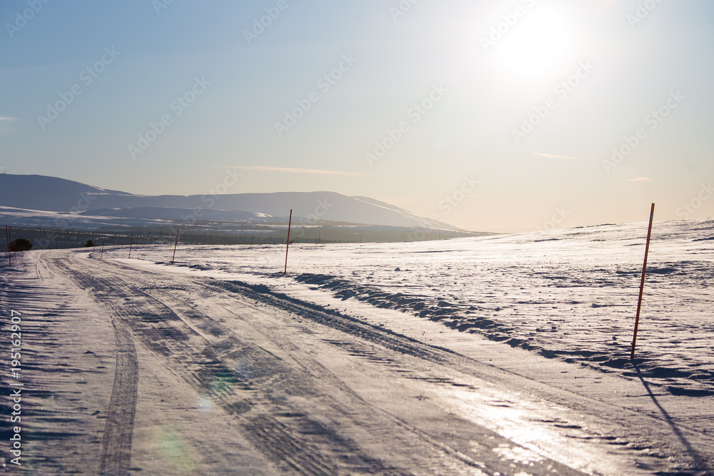 A beautiful white snowy road in central Norway with a red safety poles. Minimalist winter scenery un northern Europe.