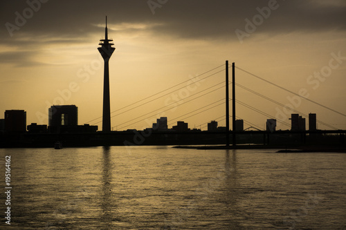 Skyline mit Brücke bei Sonnenuntergang über Fluss mit Spiegelung © Julius