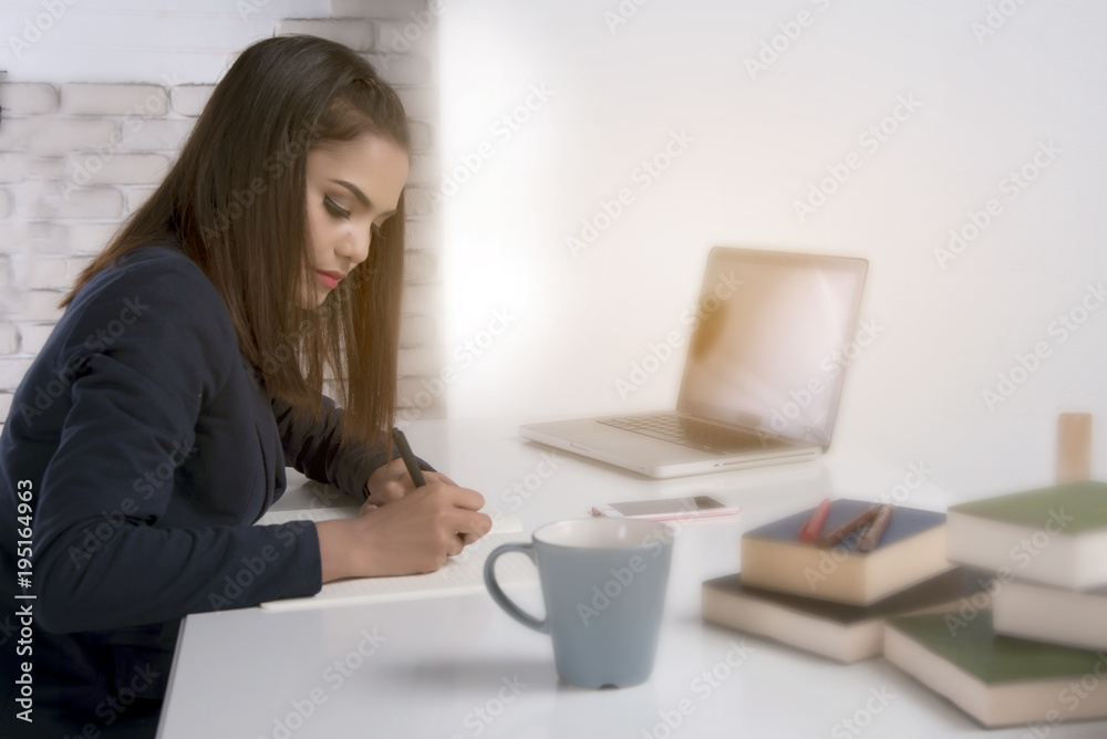 Beautiful office woman sit at table in office ,she work with laptop and use pen write report on notebook. Beautiful office woman sit at table in office ,she work with laptop and use pen write report on notebook.
