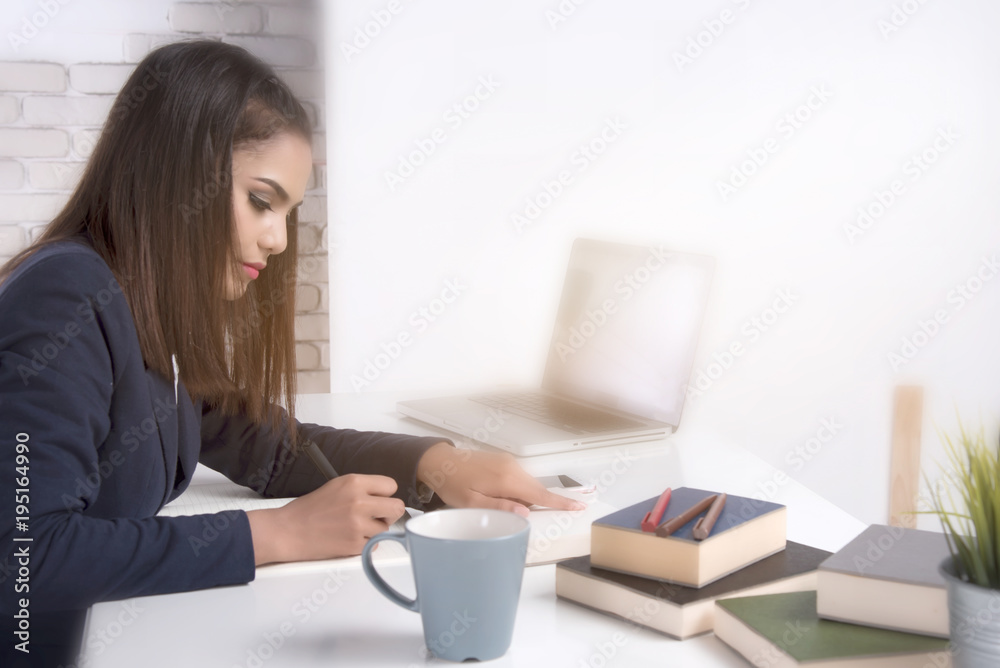 Beautiful office woman sit at table in office ,she work with laptop and use pen write report on notebook. Beautiful office woman sit at table in office ,she work with laptop and use pen write report on notebook.