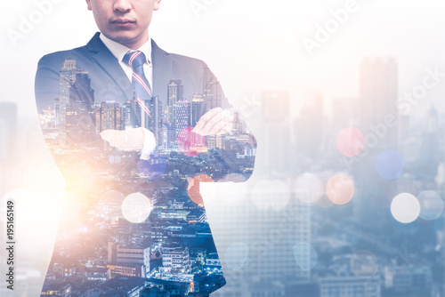 The double exposure image of the businessman standing during sunrise overlay with cityscape image. The concept of modern life, leadership, professional, business, city life and internet of things.