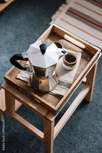 Delicious fresh morning moka coffee in traditional italian geyser coffee maker pot on a rustic wooden tray, two cups with coffee on the side