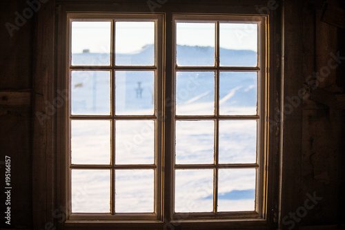 Beautiful wooden window with frozen ice flowers in Norwegian town.
