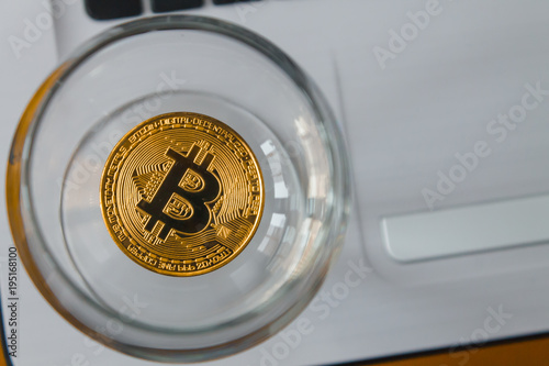 golden bitcoin in a glass on laptop background