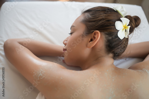 Beautiful woman getting a salt scrub beauty treatment in the health spa.