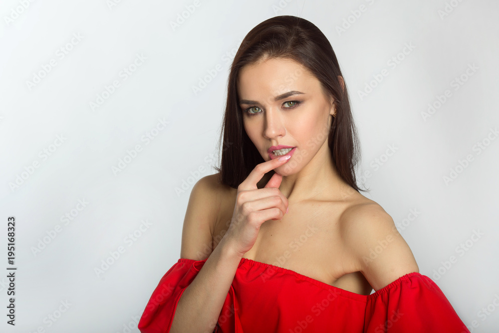 beautiful young girl in red dress on a white background with bare shoulders with a serious pensive face beautiful young girl in red dress on a white background with bare shoulders with a serious pensive face