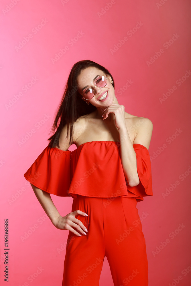 positive beautiful young girl in red attire on a pink background with bare shoulders in pink glasses positive beautiful young girl in red attire on a pink background with bare shoulders in pink glasses