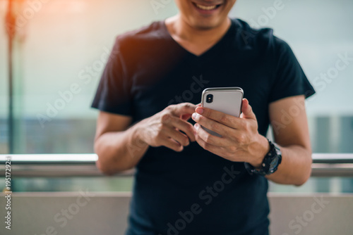 Man using smartphone with happiness while standing at Skytrain