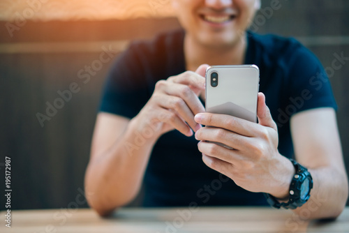 Young businessman smiling and using smartphone in restaurant