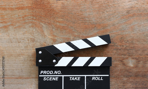 closeup movie clapper board on wood table with soft-focus and over light in the background