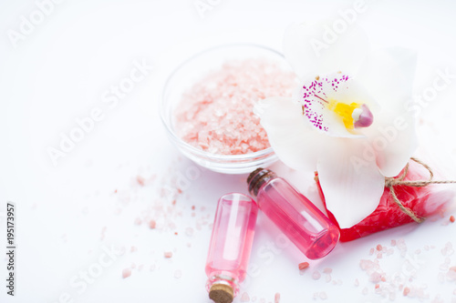 Spa and natural cosmetics concept. Set of sea salt, orchid, natural clay ,shea oil, glass bottles and other spa treatment tools on the white background. Top view. Space for a text. Close up.
