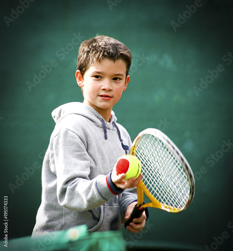 Kid tennis player on green blurred background and vignette.