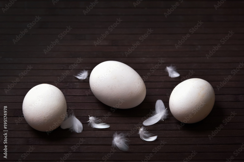eggs on a dark background with feathers