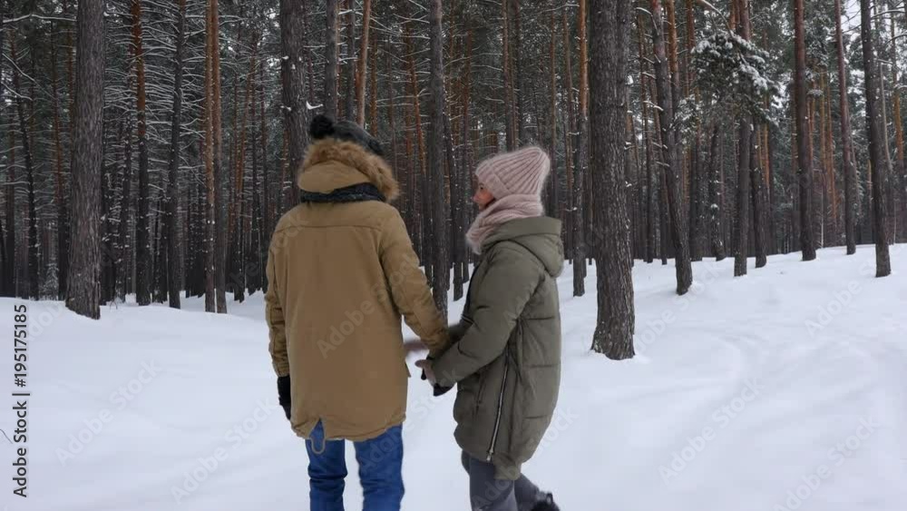 Married couple strolling along the wintry forest and holding hands together Married couple strolling along the wintry forest and holding hands together