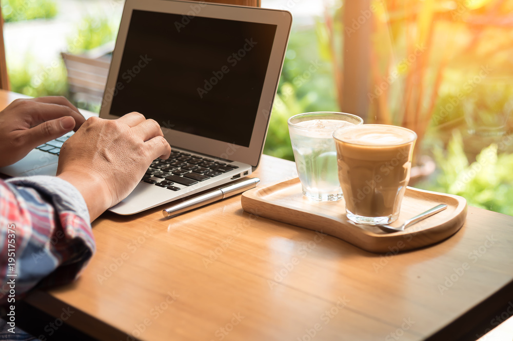 Cropped image of middle age man working on his laptop in a coffee shop. Side view of business man hands busy using laptop at office desk. Young male student typing on computer sitting at wooden table. Cropped image of middle age man working on his laptop in a coffee shop. Side view of business man hands busy using laptop at office desk. Young male student typing on computer sitting at wooden table.