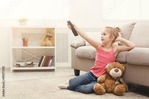 Quadro su tela Beautiful casual little girl watching tv while sitting on the floor at home