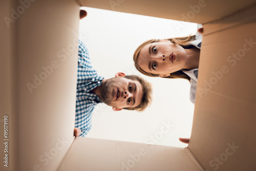 The girl and the boy are looking at the empty box. View from inside the box close-up. photo