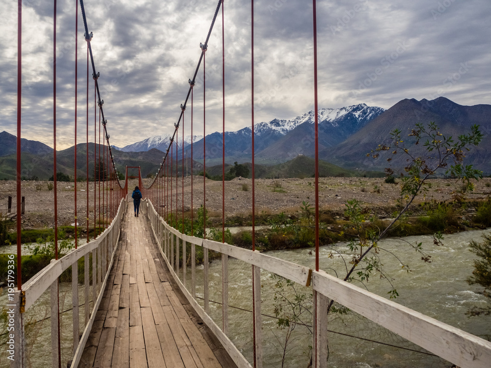 Landscape near Vicuña in Chile with a girl crossing a suspension bridge