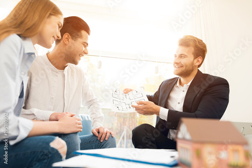 Young couple in a meeting with a realtor. Guy and girl make a contract with realtor buying property.