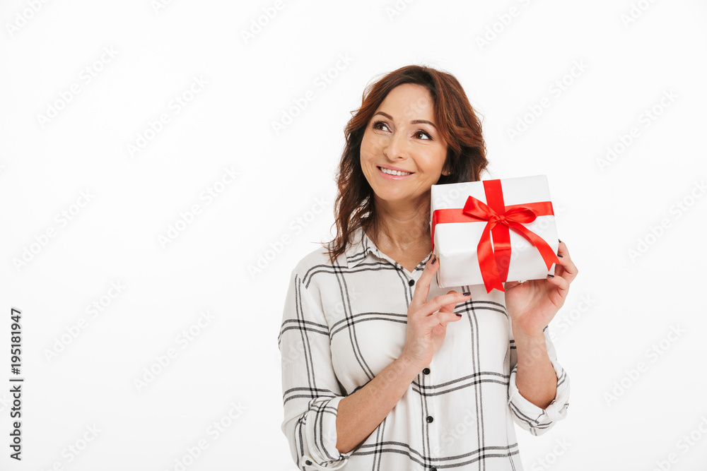 Curious woman 40s with beautiful smile holding present box in hands and trying to figure out what's inside, isolated over white background indoor Curious woman 40s with beautiful smile holding present box in hands and trying to figure out what's inside, isolated over white background indoor