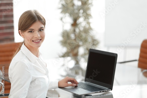 Young business woman sitting at her desk in an office, working on a laptop computer