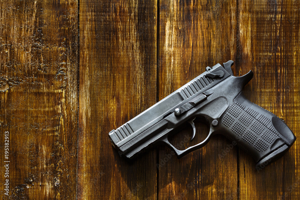 A gun against the background of a wooden