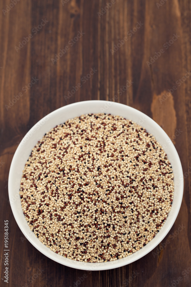 uncooked quinoa in white bowl on wooden background uncooked quinoa in white bowl on wooden background