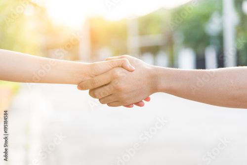 Close up on a asian women holding hands at green and sunset background.