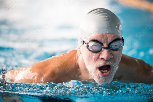 Schilderij op canvas Senior man swimming in an indoor swimming pool.