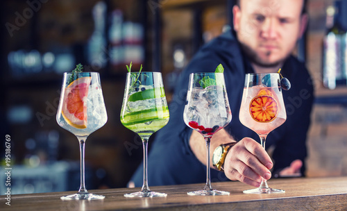 Barman in pub or restaurant  preparing a gin tonic cocktail drinks in wine glasses photo