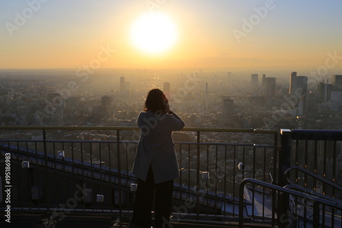 Photography office lady watch the sunset on the top of skyscraper in tokyo