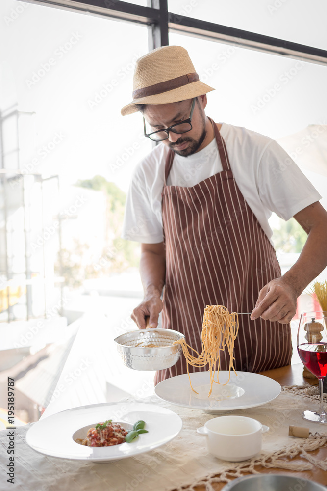Handsome bearded cheef cook prepairing spaghetti on a kitchen, Chef cooks meal Handsome bearded cheef cook prepairing spaghetti on a kitchen, Chef cooks meal
