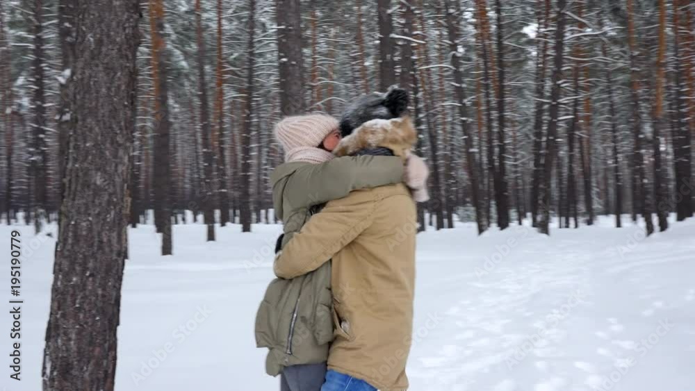 Woman attempting to shake off snow from the hat of her husband Woman attempting to shake off snow from the hat of her husband