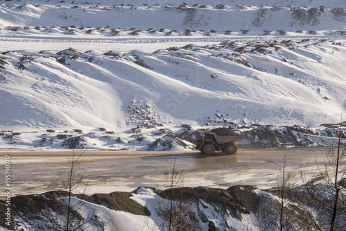 Dump truck carrying a big load across an open pit mine in winter photo